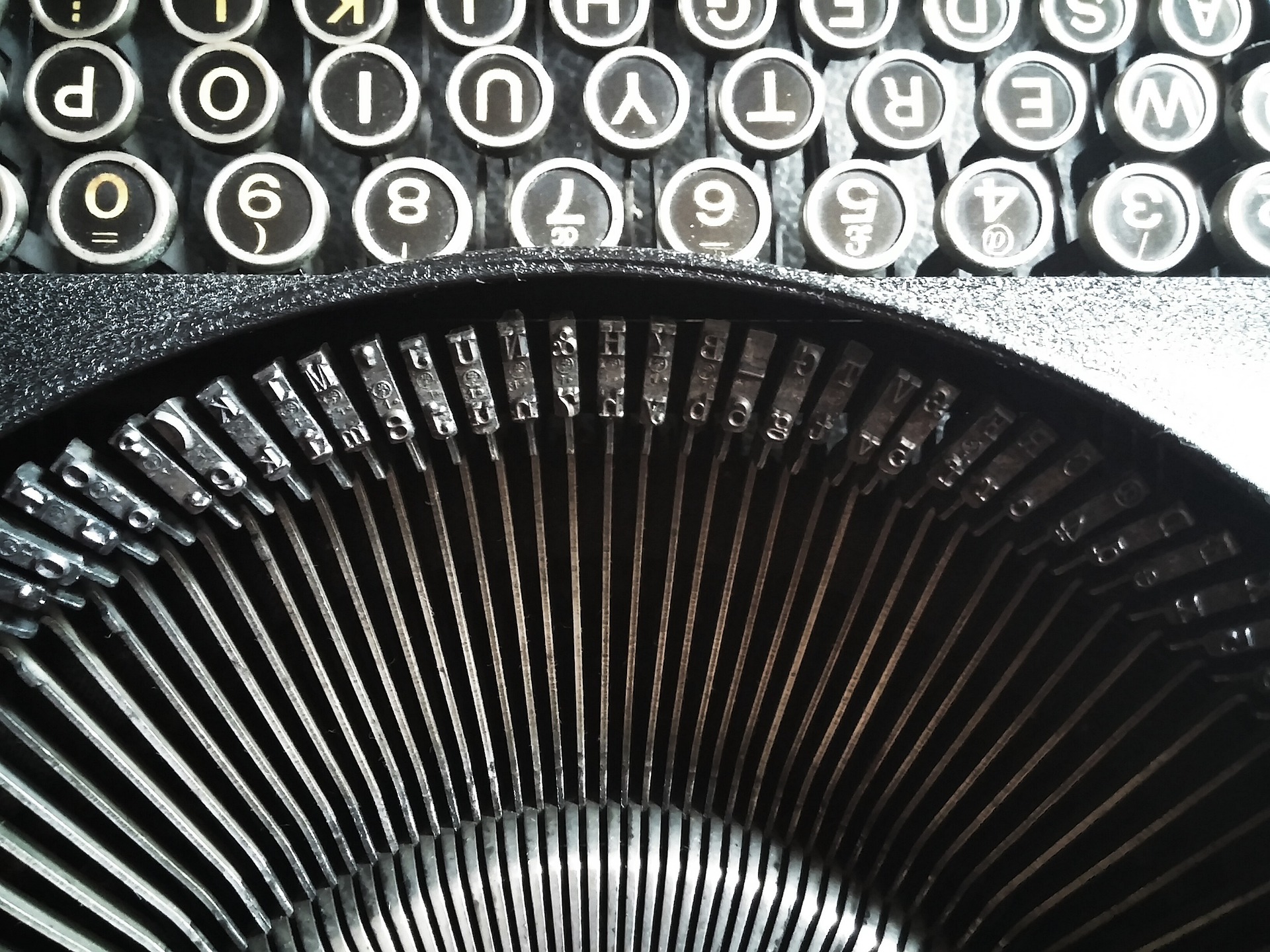 A closeup of the insides of a typewriter with keys arranged in an array across the photograph laterally