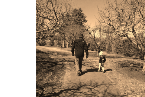 Black and white sepia-colored photo of 2 figures walking along a path