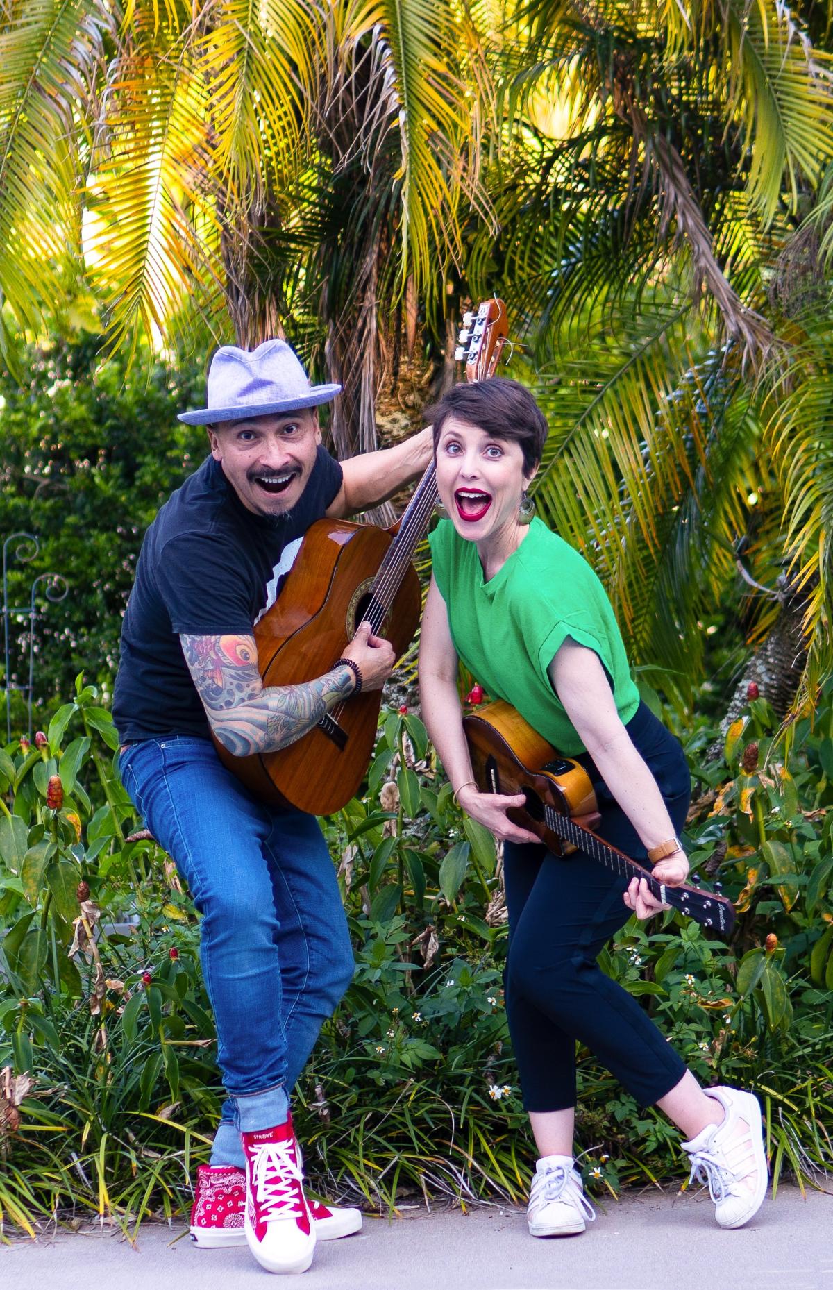 A man holds a guitar and a woman holds a ukelele primed to play.