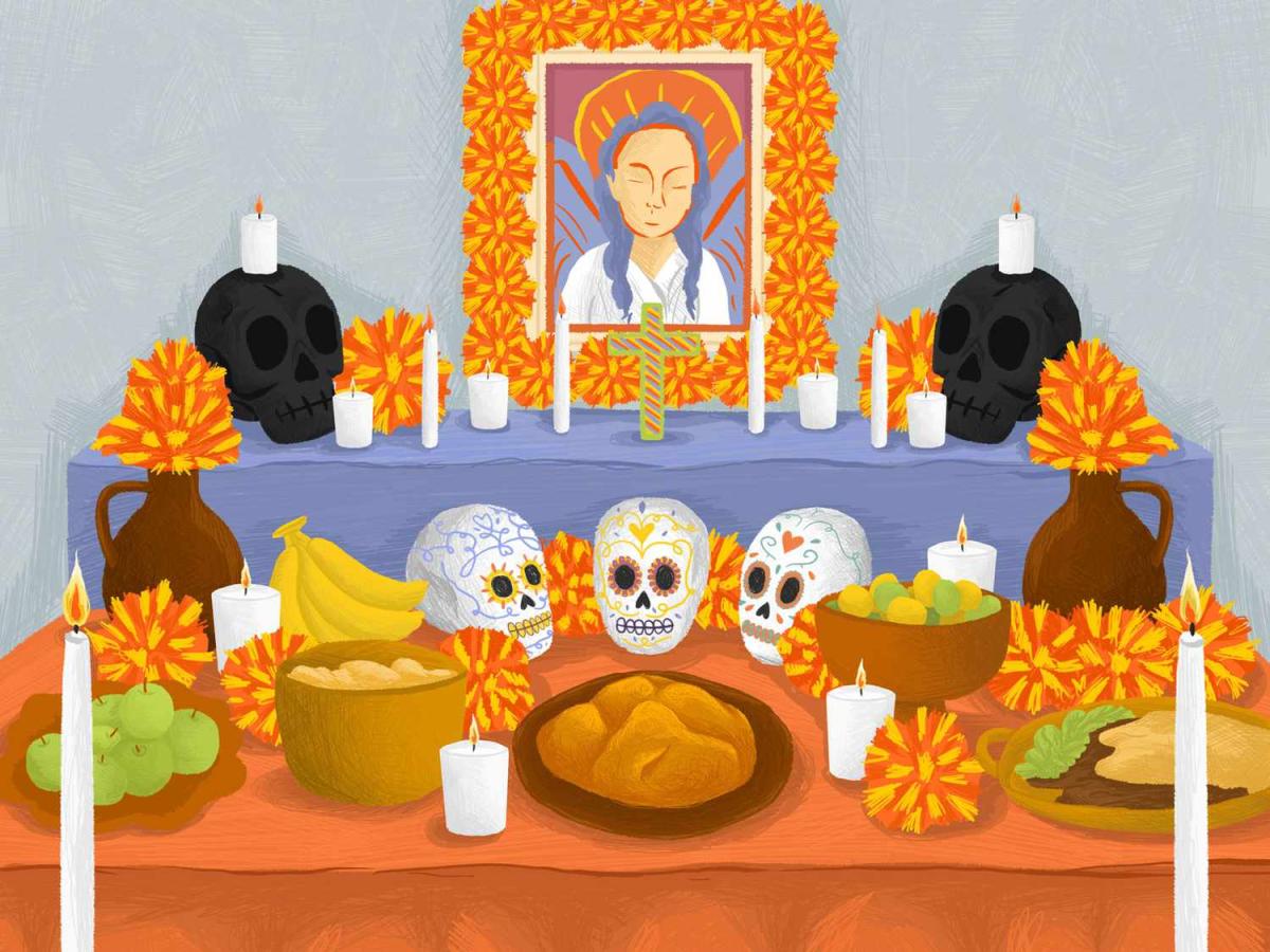 Altar for day of the dead with orange table cloth, skulls, candles, bread of the dead